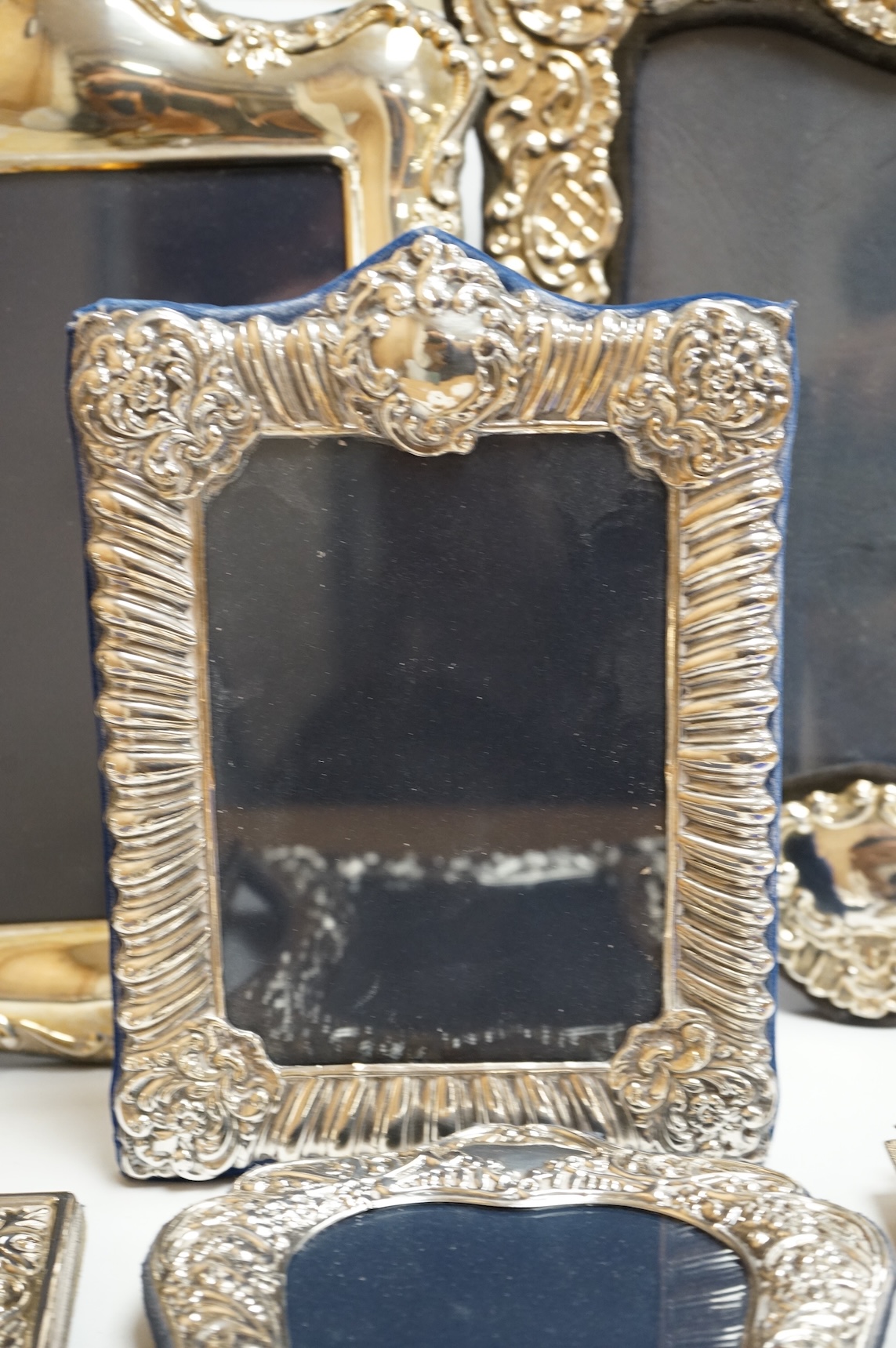 A George V silver mounted rectangular photograph frame, with ribbon bow crest, by Stokes & Ireland Ltd, Chester, 1912, 18.2cm including crest, together with ten other modern silver mounted photograph frames, largest 29.4